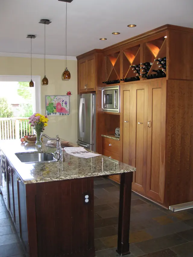 Kitchen with floor-to-ceiling cherry cabinetry, granite island, and pendant lighting