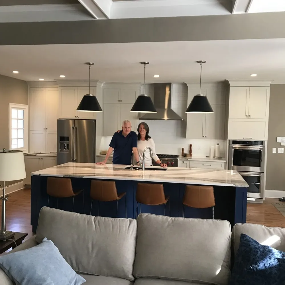 Homeowners standing at the navy island of their newly remodeled kitchen